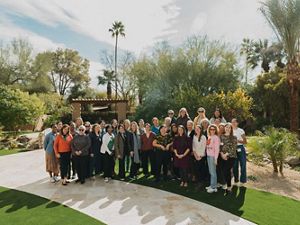 A group of women gather for a group photo outside at an event.