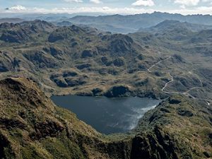 Aerial view looking down on a lake surrounded on all sides by tall mountains.